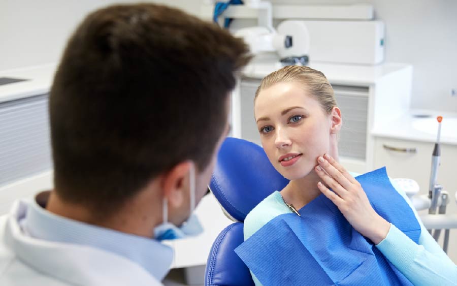 Woman in dental exam room talking to dentist